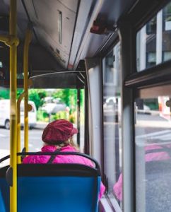 A woman wearing a pink outfit sits on a city bus in Trento, Italy, capturing urban commuting life.