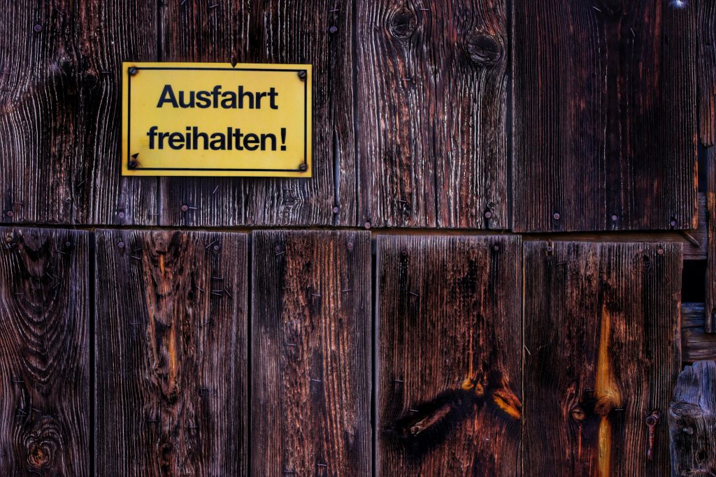 Weathered wooden wall with a German 'Keep Exit Clear' sign.