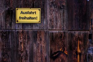 Weathered wooden wall with a German 'Keep Exit Clear' sign.