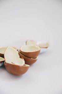 Close-up of a broken cream-filled chocolate egg on a white background.