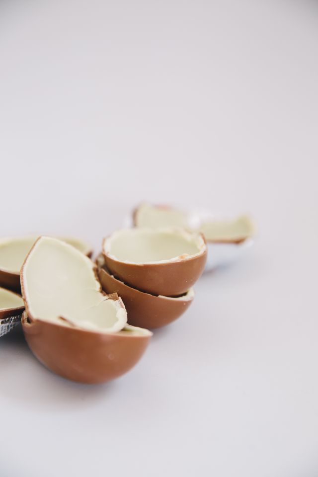 Close-up of a broken cream-filled chocolate egg on a white background.